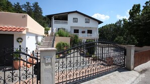 Una casa de dos pisos con fachada blanca, un balcón y una reja de hierro negro.