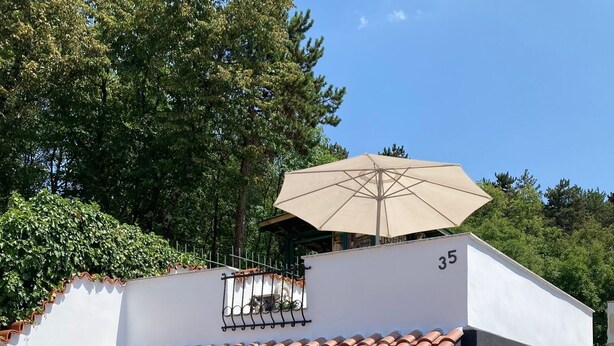 Un edificio blanco con techo de tejas rojas, una puerta con buzón y el número '35' en la pared.