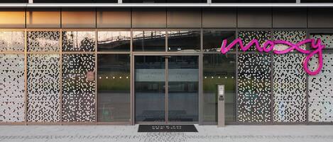 A building with a glass facade and a neon sign reading "moosy".