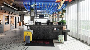 A modern hotel lobby with a reception desk, check-in counter, and a large window with a view. - Moxy Cologne-Bonn Airport (Cologne)