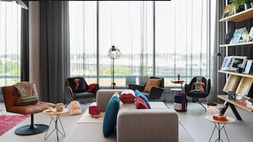 Una sala de estar moderna con un sofá, sillas, una mesa de centro y una estantería.
