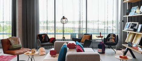 Una sala de estar moderna con un sofá, sillas, una mesa de centro y una estantería.