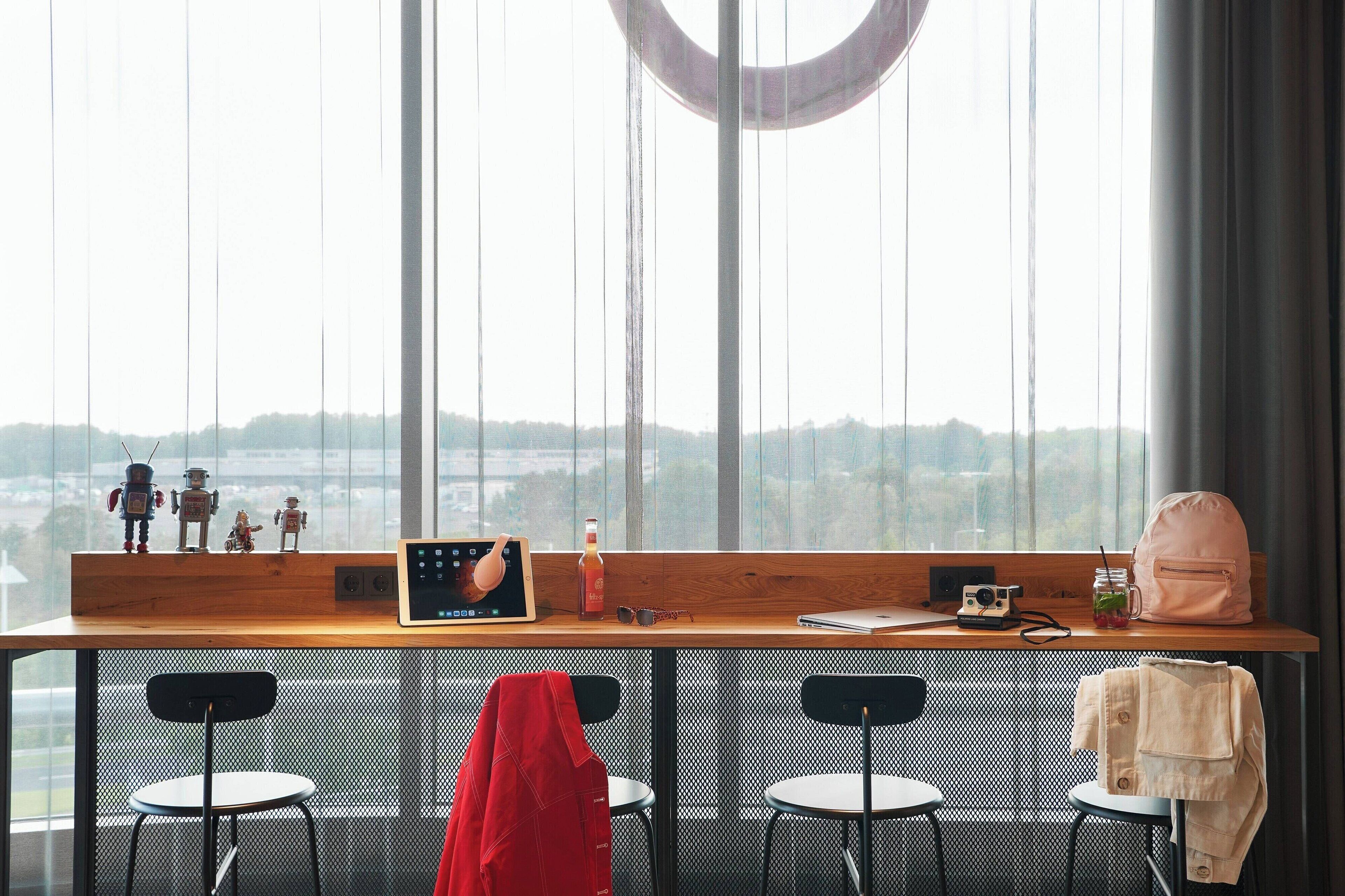 A modern room with a large window, a wooden desk, two chairs, and a view of a distant landscape.