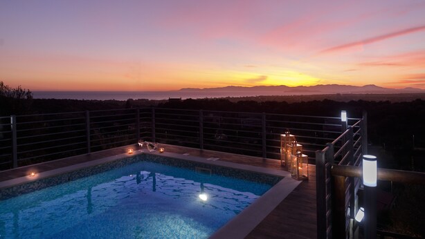A rooftop pool with a view of the sunset and mountains.
