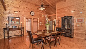 A wooden-paneled room with a dining table, chairs, a chandelier, a clock, and a cabinet. - ⛰️Tuscan Vista🍃Pet Friendly, Fenced Yard, Single-Level, Hot Tub & Game Room (Sevierville)