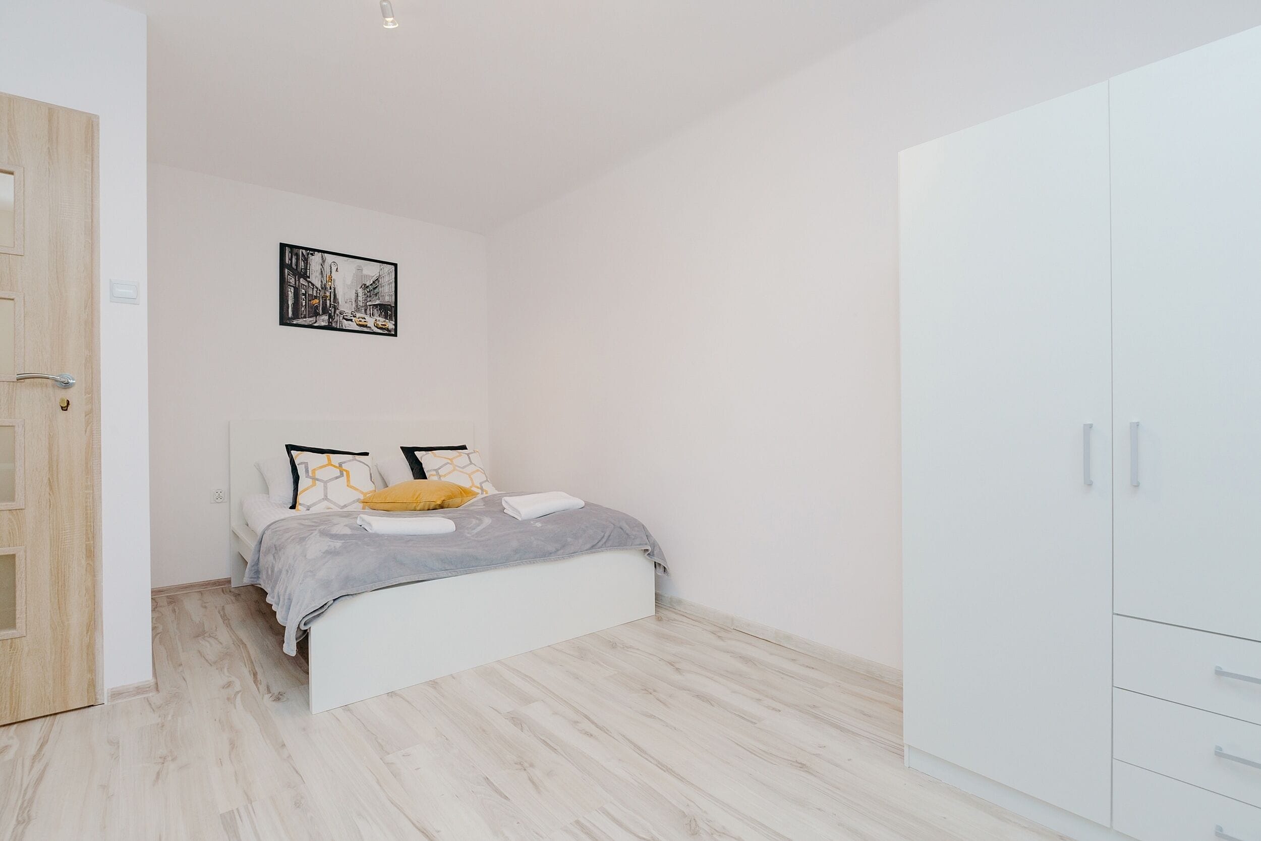 A bedroom with a bed, a wardrobe, and a framed picture on the wall.