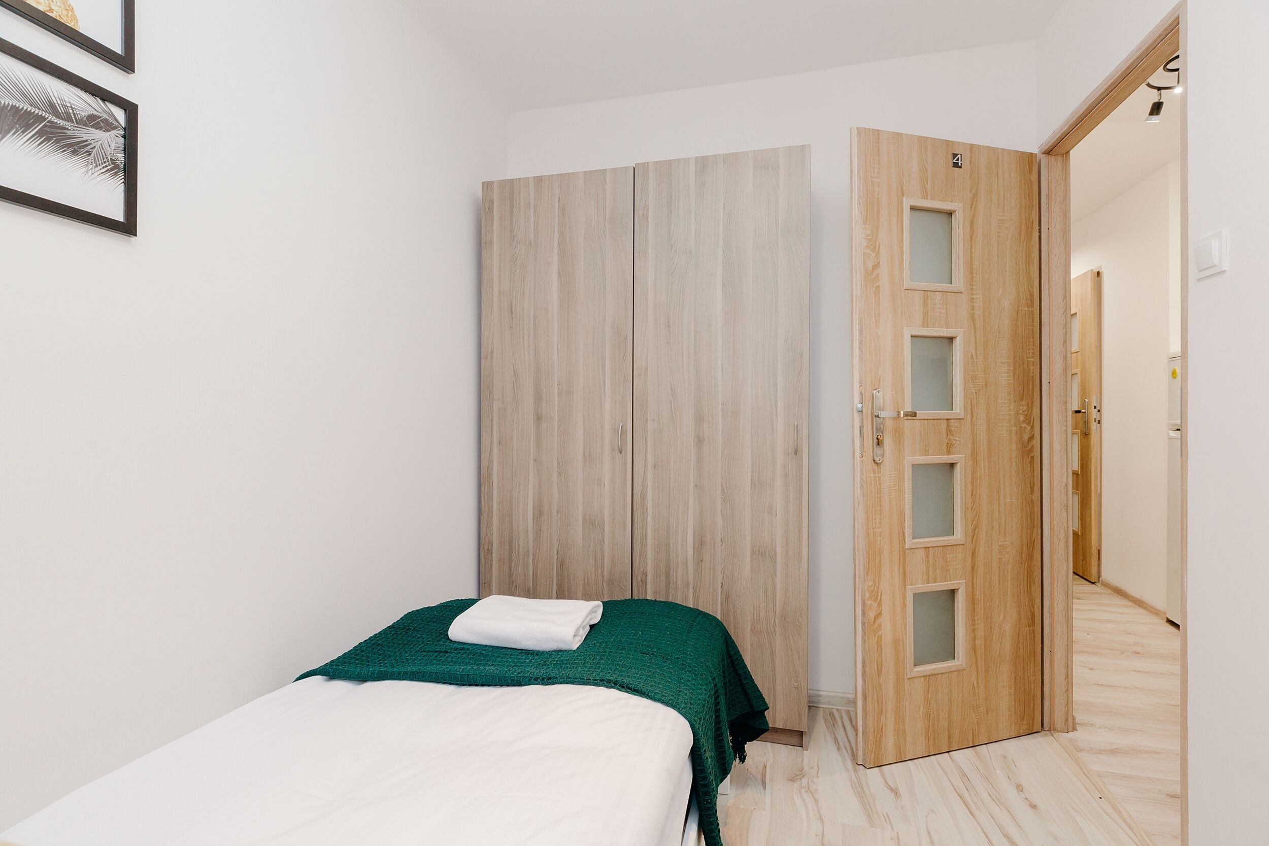 A bedroom with a bed, a wardrobe, and a door leading to another room.