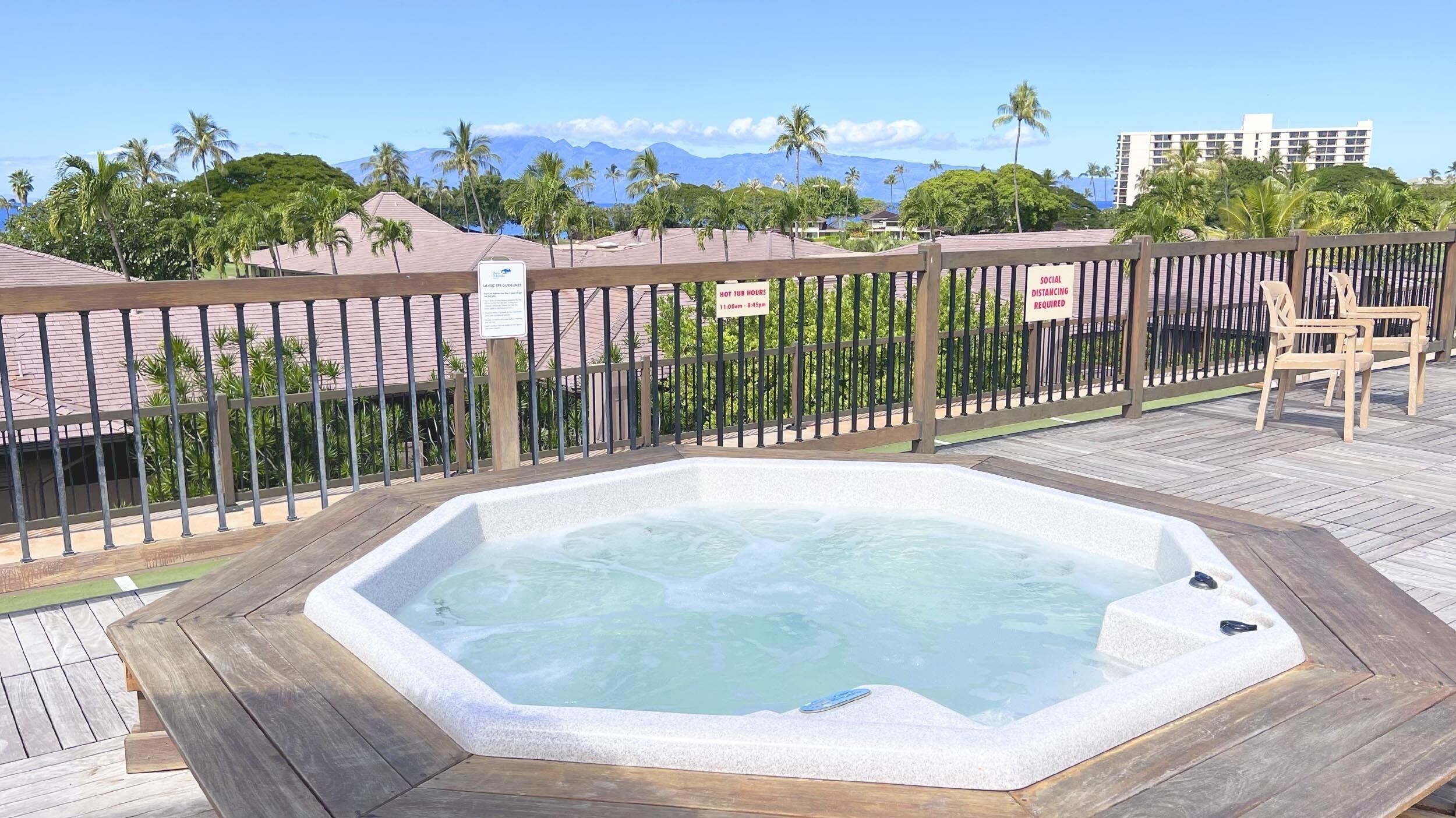 A hot tub with a wooden deck and a wooden fence.