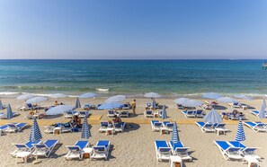 A beach with rows of sun loungers and striped umbrellas, a wooden deck, and the sea in the background. - Relax Beach Hotel - All inclusive (Alanya)