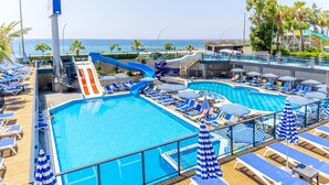 Cubierta de un crucero con dos piscinas, sillones de sol y un tobogán de agua.