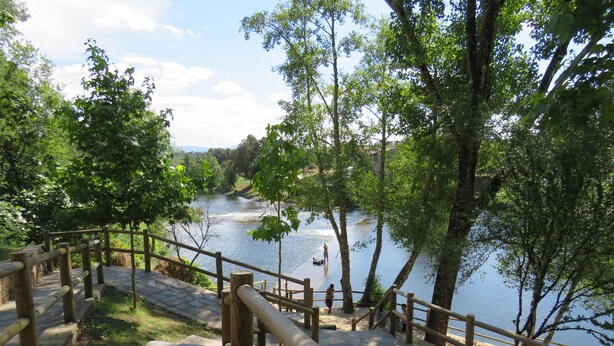Un escalier en bois mène à une zone riveraine offrant une vue sur le fleuve et la végétation environnante.