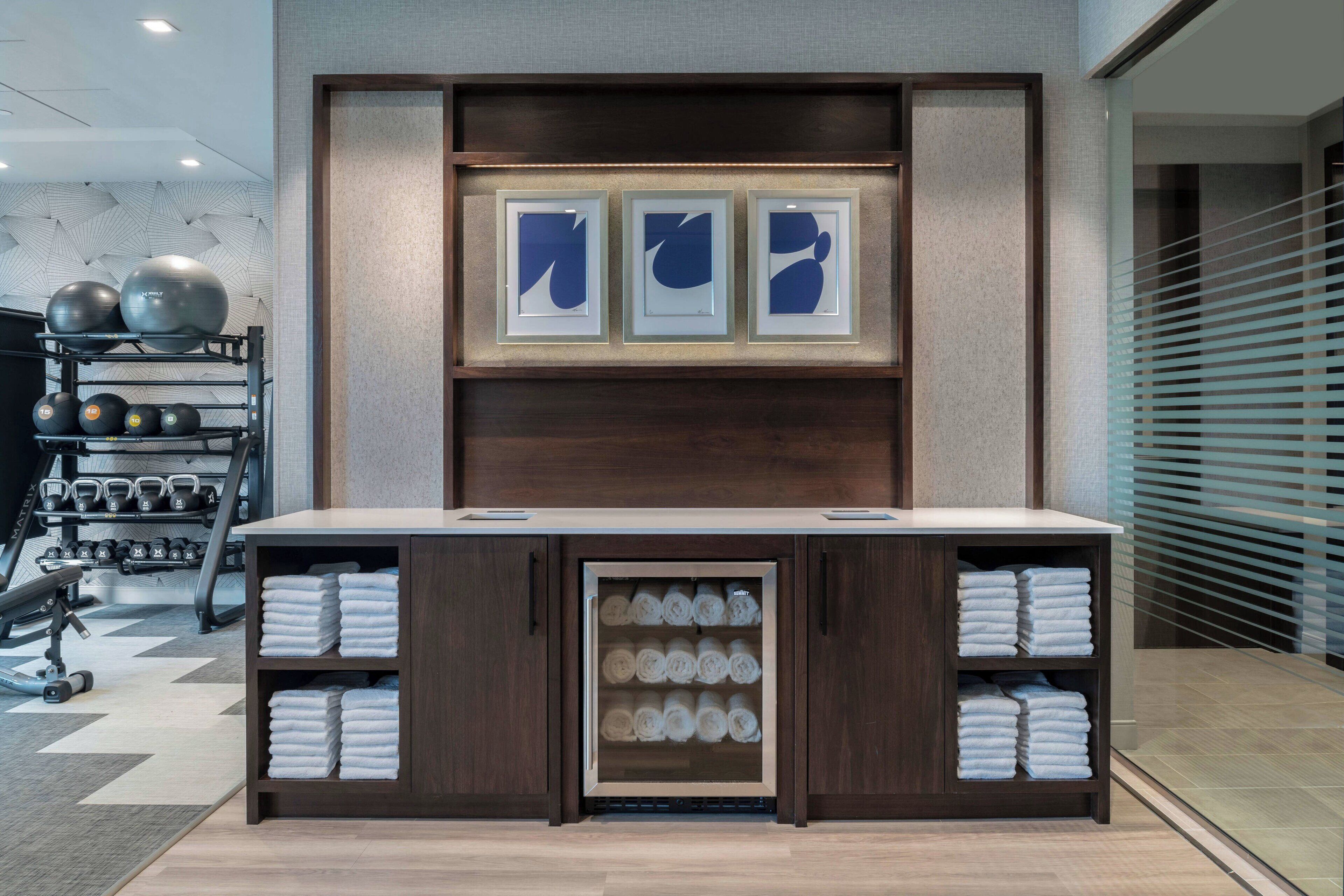 A reception area with a wooden reception desk, framed artwork, and a towel rack with neatly folded towels.