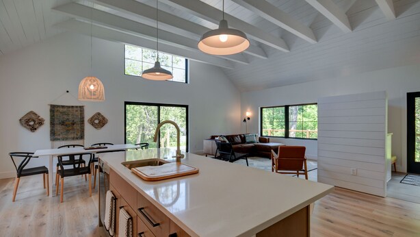 A spacious kitchen with a large island, wooden flooring, and pendant lighting. - Modern home in Glen Arbor. Steam shower. Walk to lake. Air conditioning. (Glen Arbor)