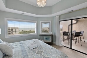 Relax in a stylish room with a large bed, adjacent dining area, and a balcony offering a view of the surrounding buildings.