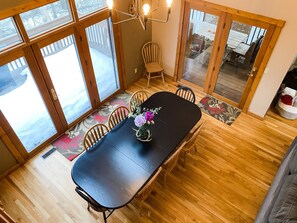 Un coin repas avec une table noire, des chaises en bois et un centre de table floral.