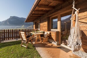 Une cabane en bois dotée d’une terrasse, d’un hamac et offrant une vue sur les montagnes.