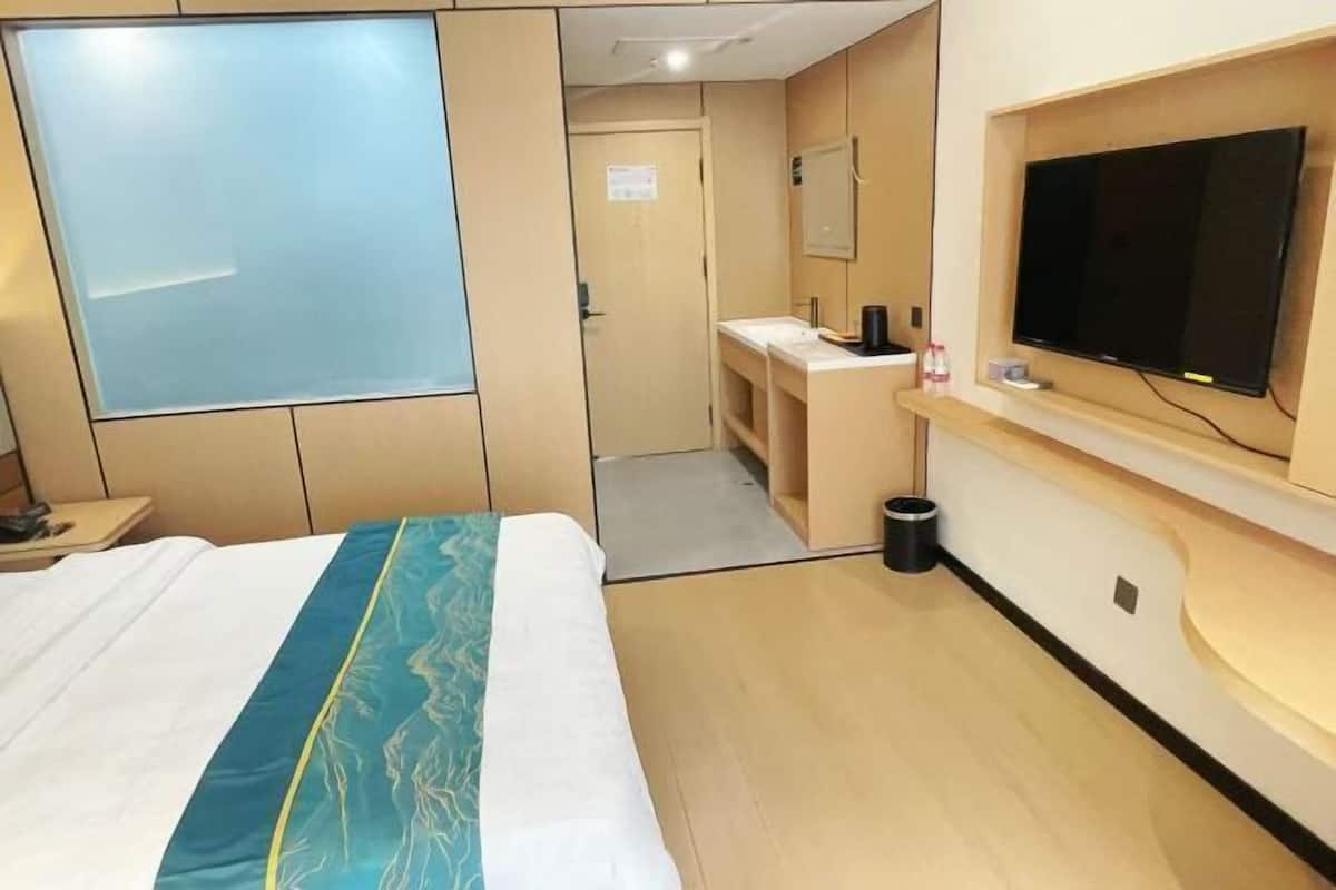 A hotel room with a bed, a TV, a desk, and a bathroom.