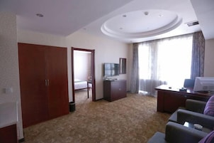 Habitación de hotel con un armario grande, un escritorio con computadora, televisión y una cama al fondo.