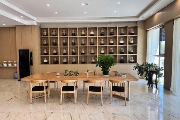 Un coin repas avec une longue table en bois et des chaises, un mur recouvert de bocaux en verre et une plante en pot.