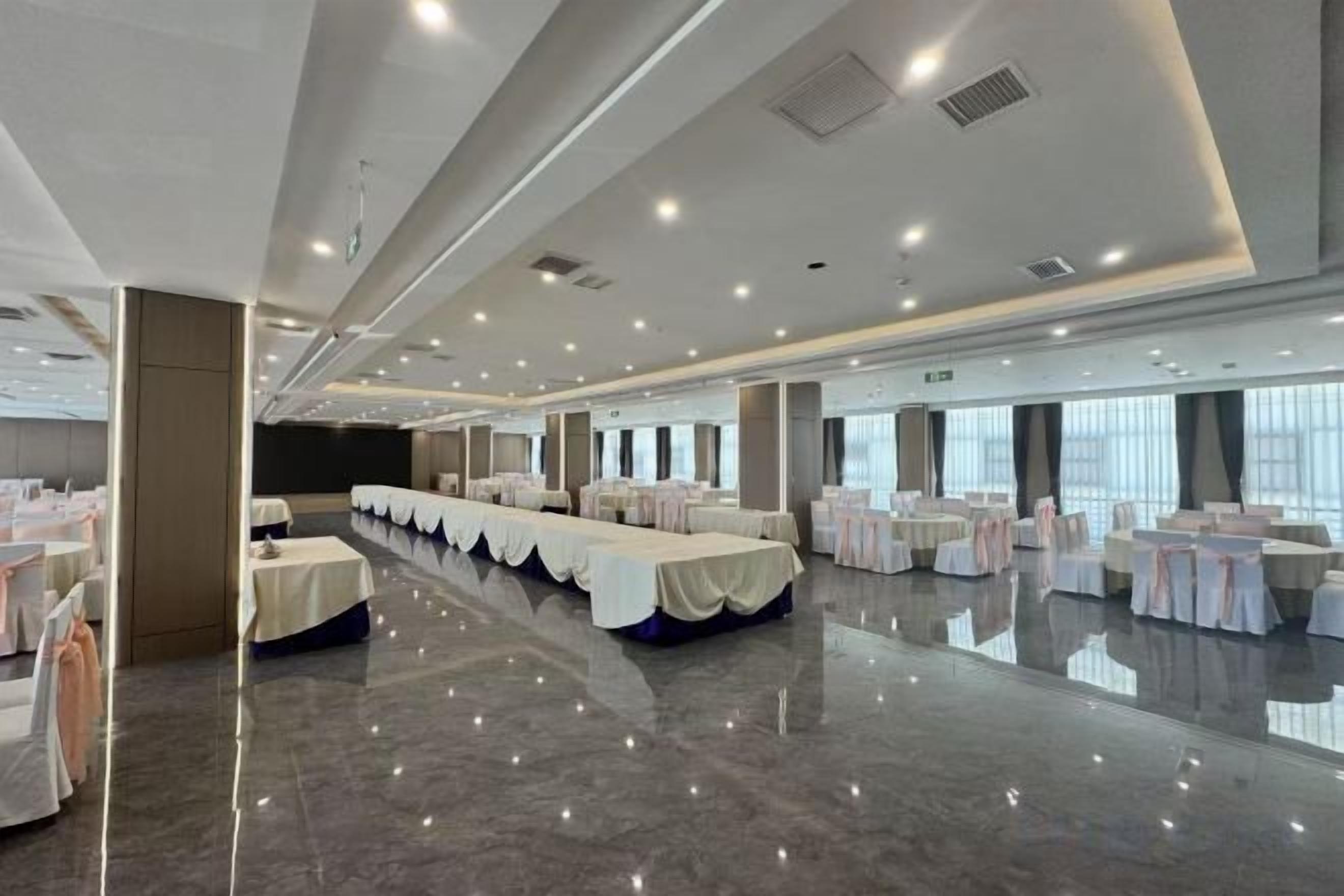 A large banquet hall with long tables, chairs, and a polished floor.