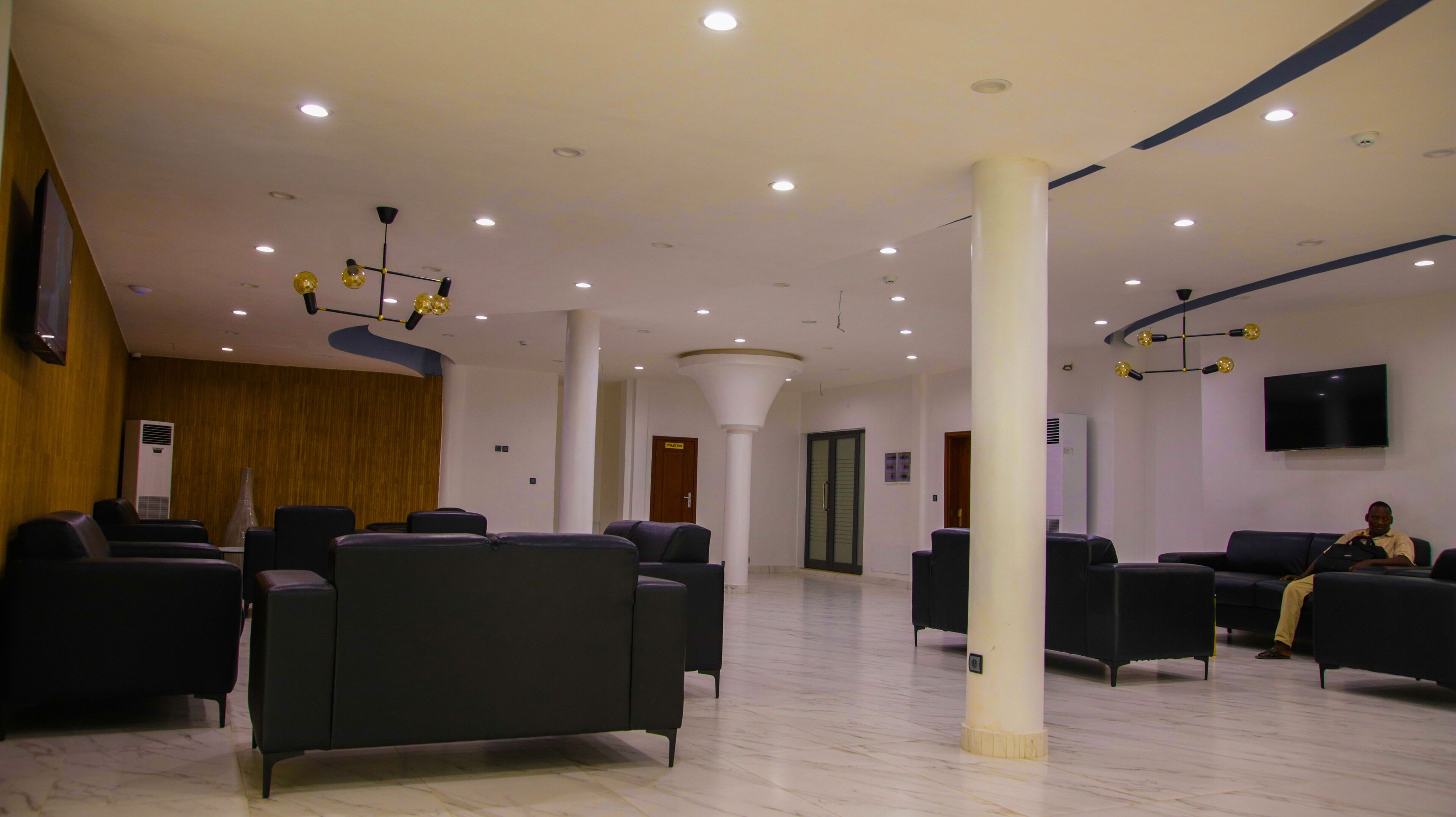 A spacious lobby with modern seating, a large pillar, and a flat-screen TV mounted on the wall.