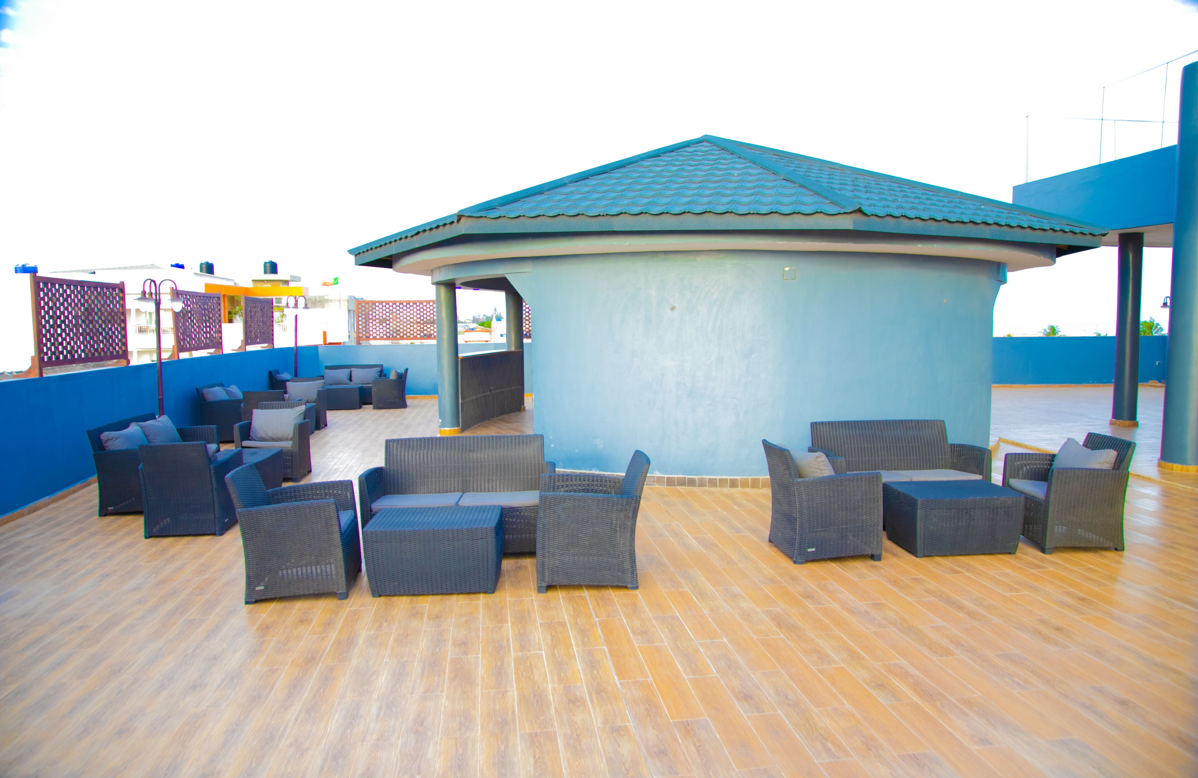 A covered outdoor seating area with wicker furniture and a blue-roofed structure.