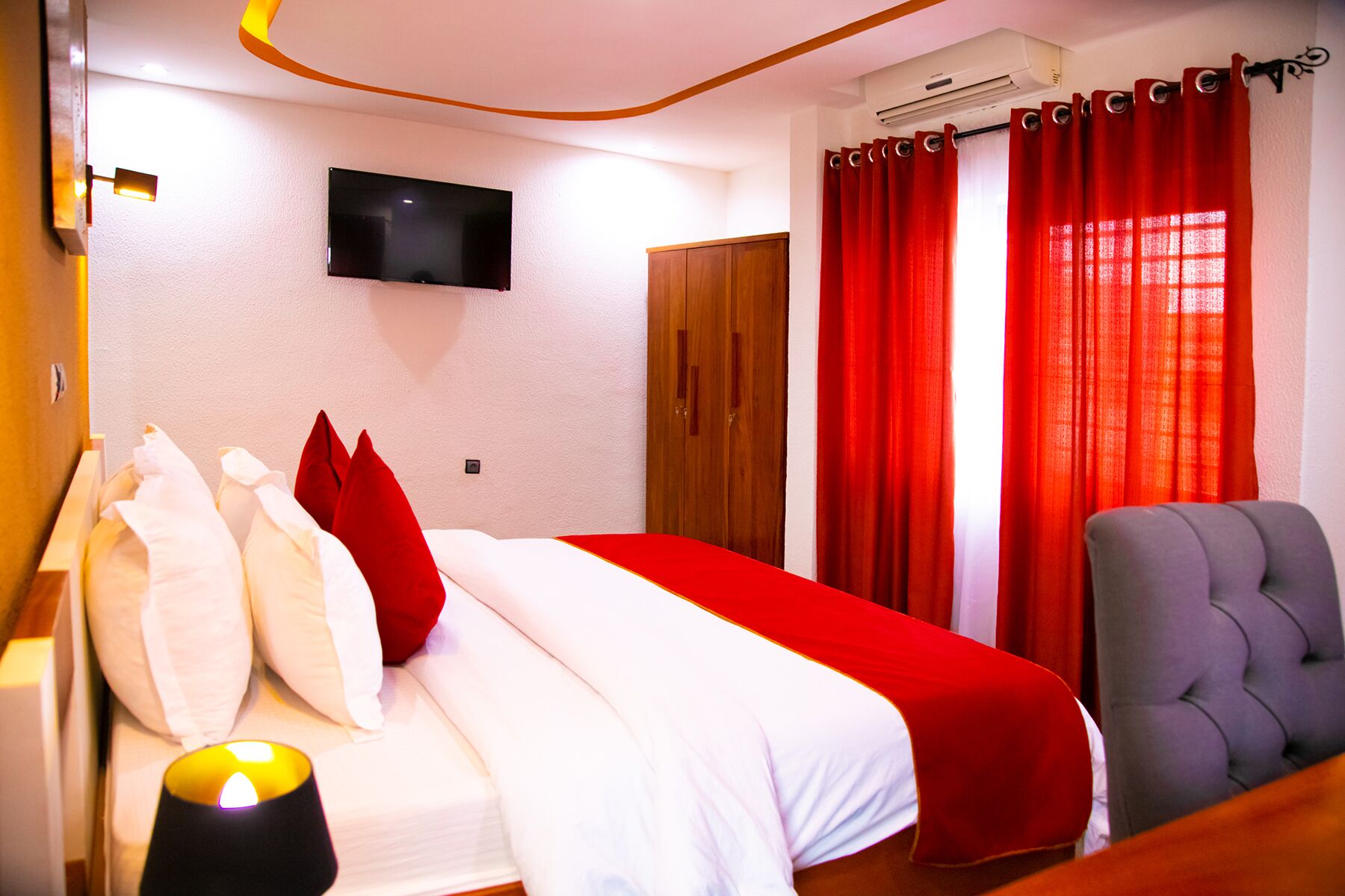 Una habitación de hotel con cama, televisión, armario y silla.
