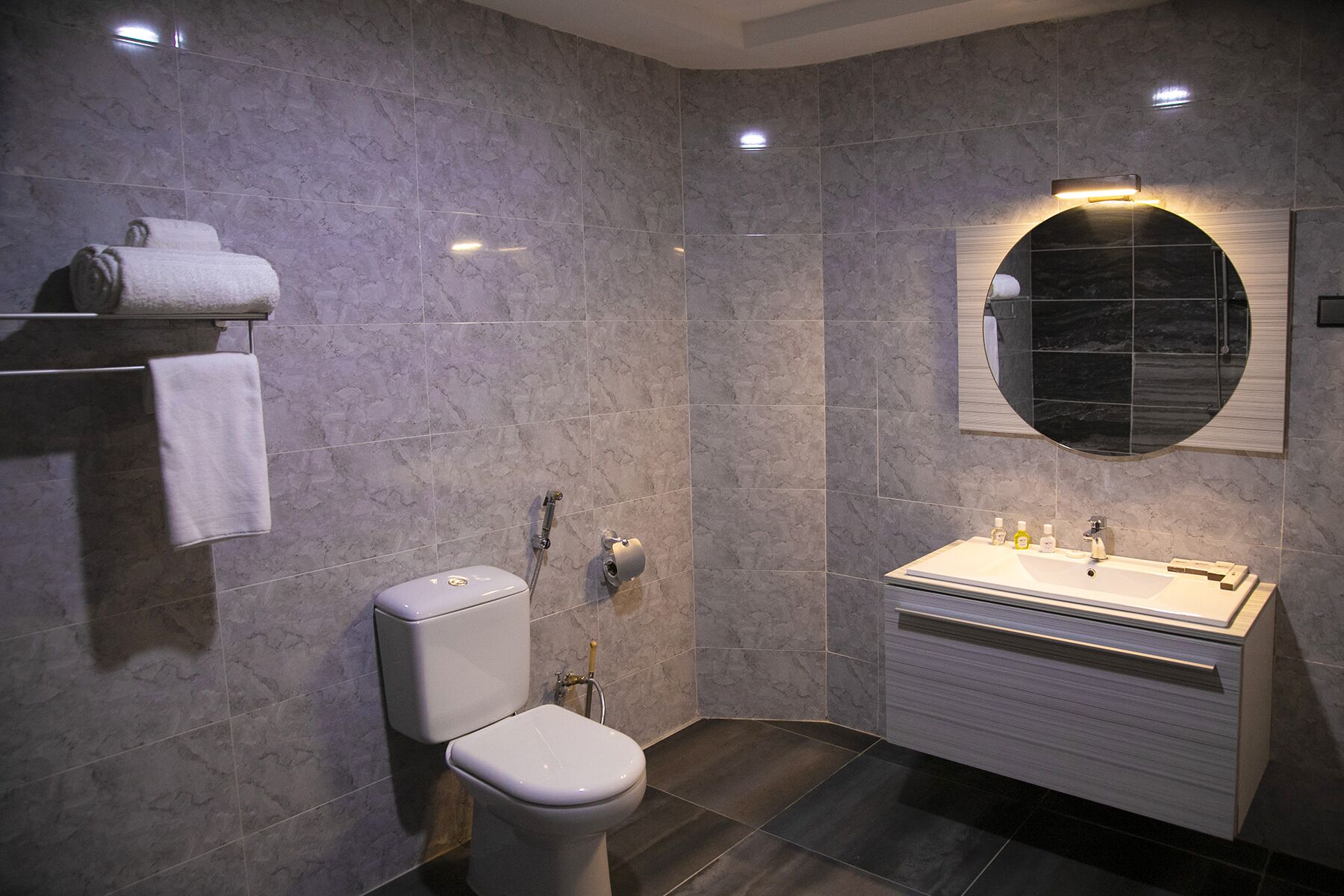 A modern bathroom with a toilet, sink, and mirror.