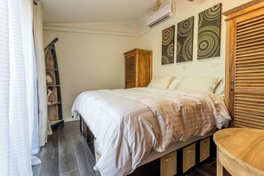 A bedroom with a bed, a wooden wardrobe, and a shelf with decorative items. - Top Spot: 1BR w Private Patio near Palm Beach (Noord)