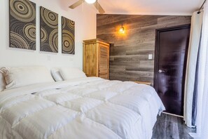 A bedroom with a bed, a wooden wardrobe, and a wall-mounted light fixture.