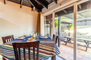 Ein Essbereich mit einem Tisch für vier Personen, eine Schiebetür zu einer Außenpatio und Blick auf die Patio.