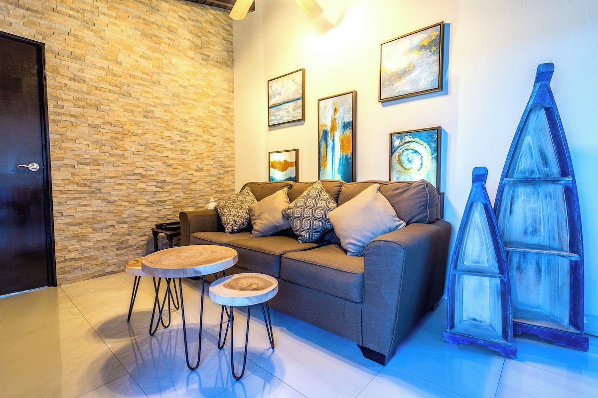A modern living room with a sofa, two round tables, and decorative items on the wall.