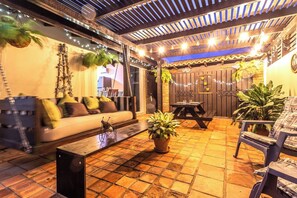 Un área de patio al aire libre con un sofá, sillas, una mesa y plantas en macetas.