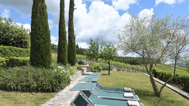 A row of green lounge chairs with towels, a stone pathway, and tall cypress trees in a landscaped garden. - Dionisia, Capannole, Gaiole in Chianti, Siena and Chianti (Gaiole in Chianti)