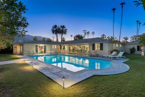 A house with a swimming pool, outdoor furniture, and palm trees.