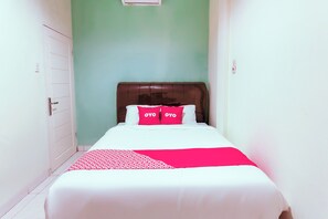 A narrow hotel room with a bed, a wooden headboard, and a green wall. - OYO 3493 Nami House (Medan)