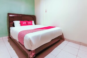 A neatly made bed with a white and red bedspread, two bright pink pillows, and a brown headboard. - OYO 3493 Nami House (Medan)