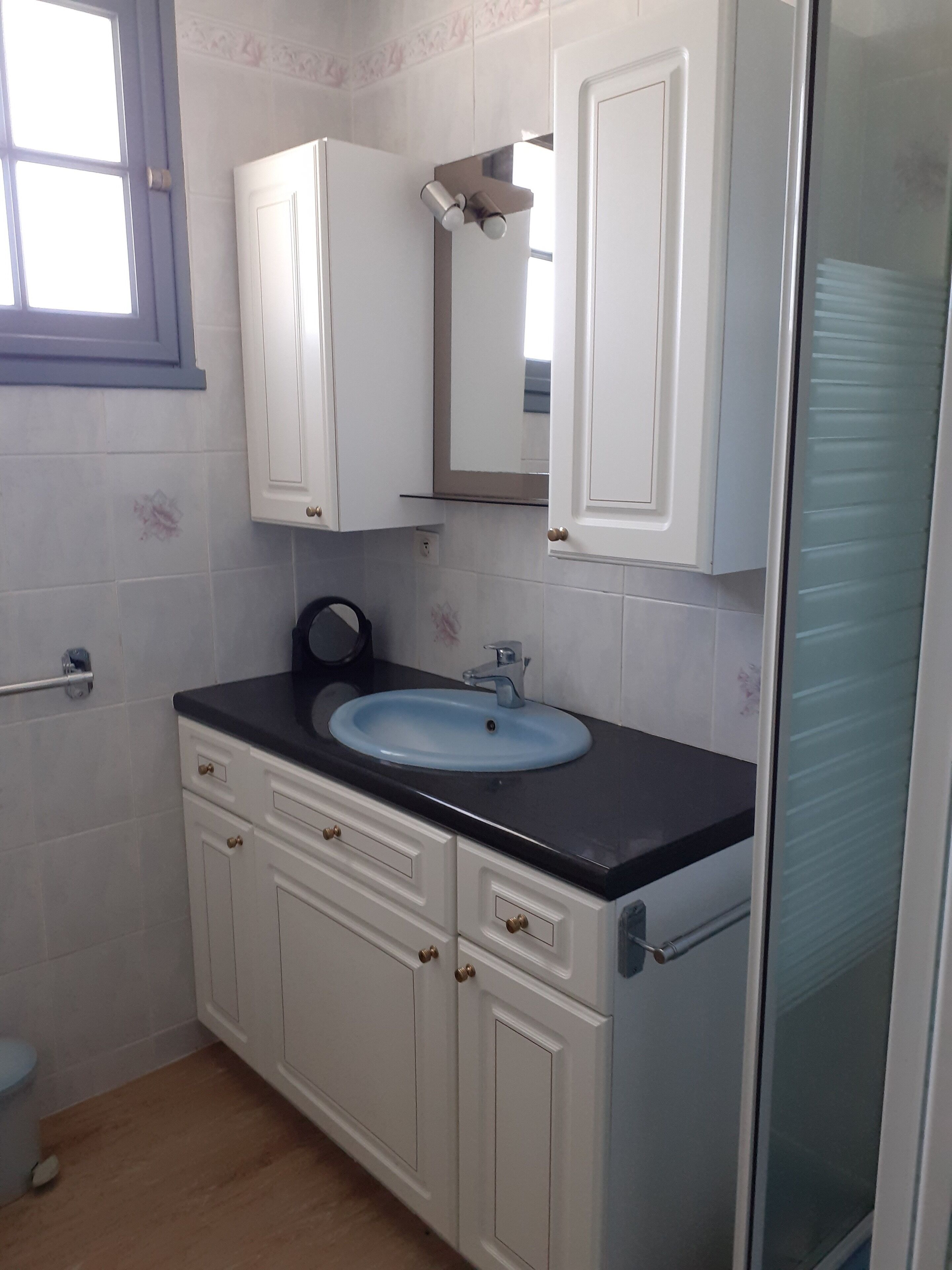 A bathroom with a white sink, a mirror above it, and white cabinets.