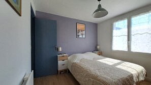 Une chambre à coucher avec un lit, des tables de chevet, une fenêtre et un tableau accroché au mur.