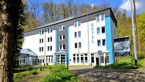 Un hôtel moderne, reconnaissable à son grand panneau « HÔTEL », doté d’un espace de réception et d’un panneau indiquant un parking situé à Rheinsteg.