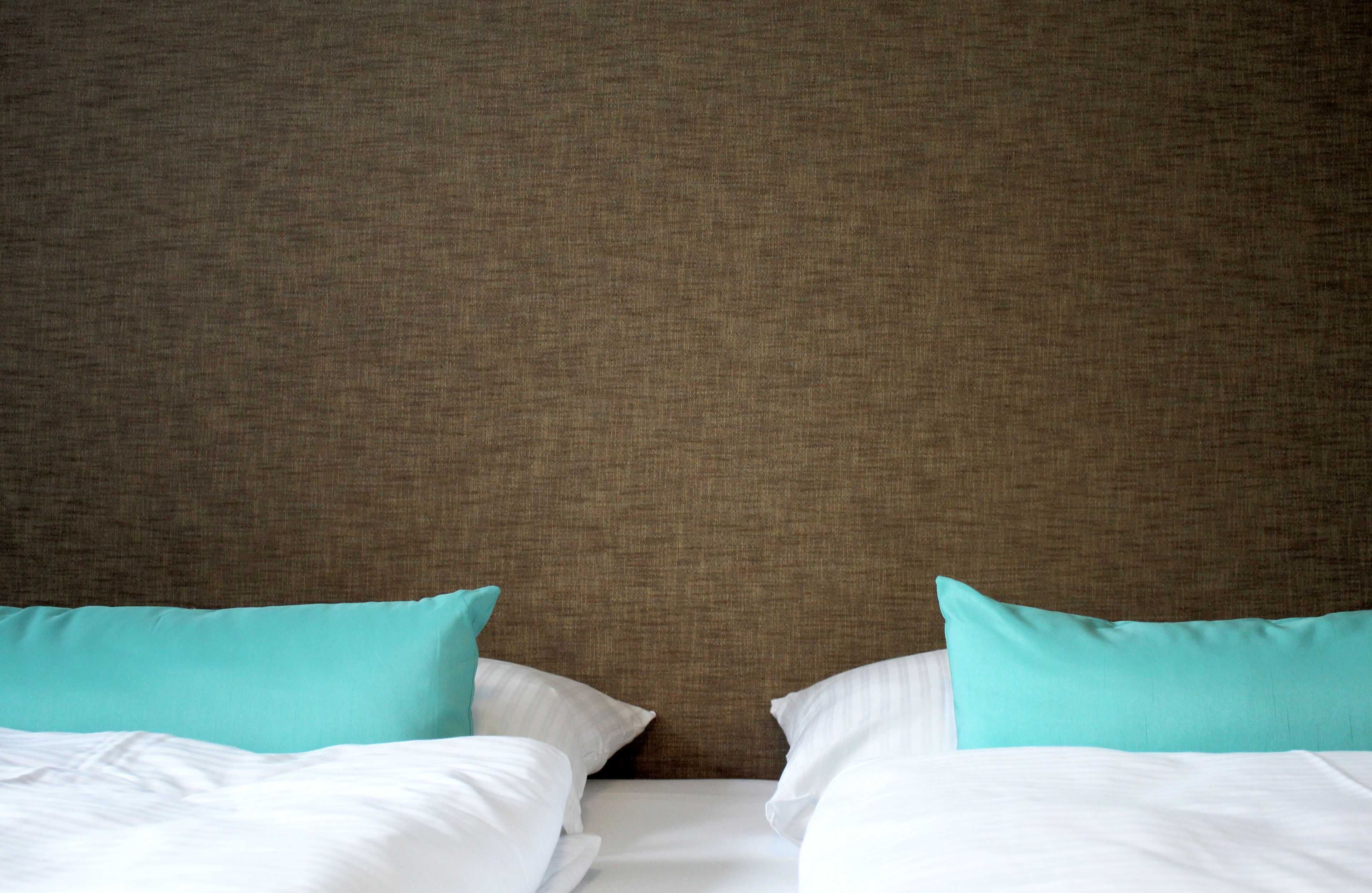 A hotel room with a large bed, two pillows, and a headboard.