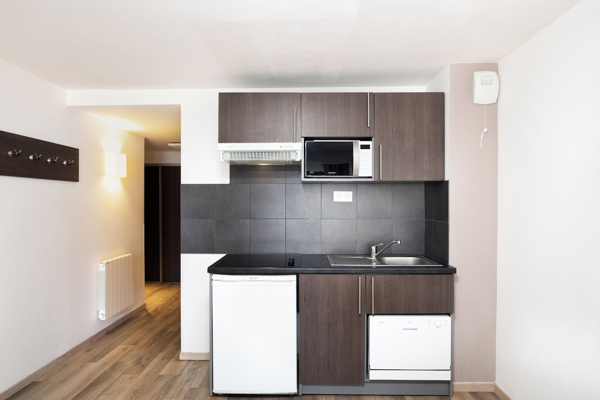 A modern kitchen with dark wooden cabinets, a black countertop, a white refrigerator, a microwave, and a dishwasher.
