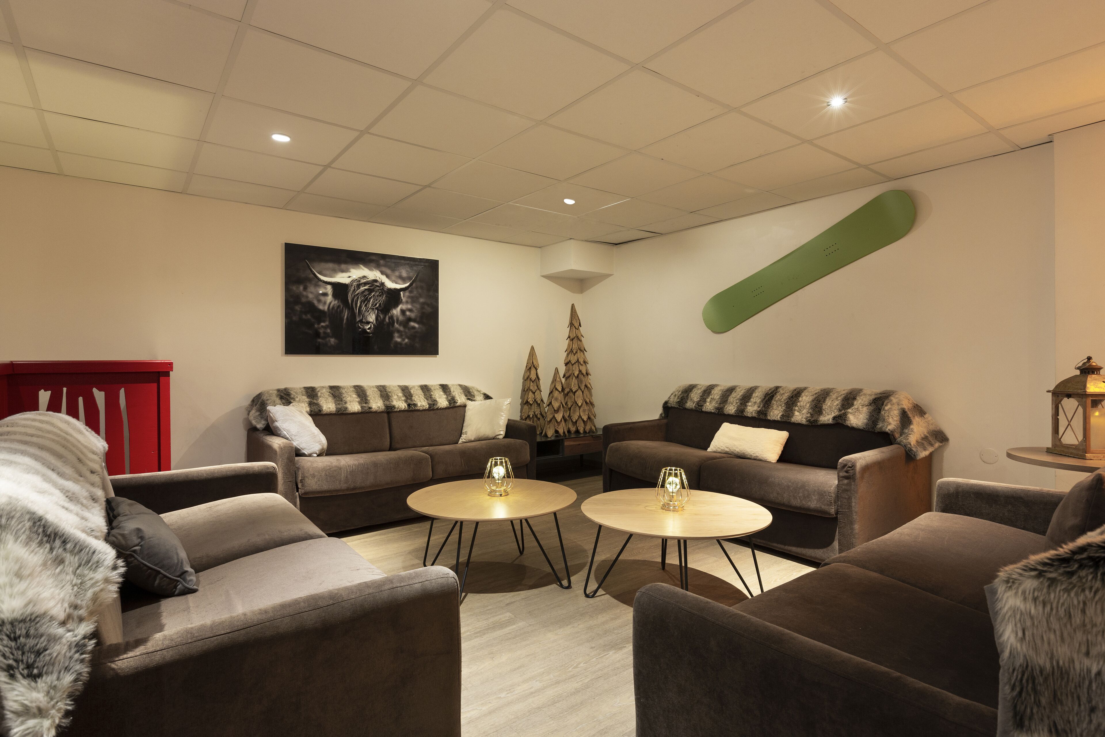 Una sala de estar moderna con dos sofás, dos mesitas redondas y una decoración de snowboard verde grande en la pared.
