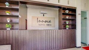 A reception desk with a sign reading "Innona Suites Home" and a cash register.