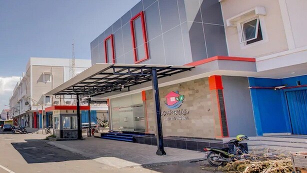 A commercial building with a covered entrance, a glass facade, and a logo on the wall.