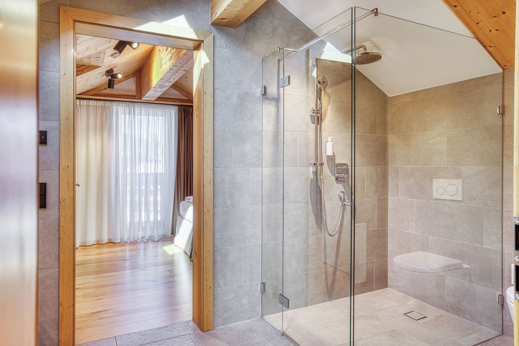 Un baño moderno con ducha de vidrio, techo de madera y un perchero visible.