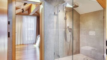 Un baño moderno con ducha de vidrio, techo de madera y un perchero visible.