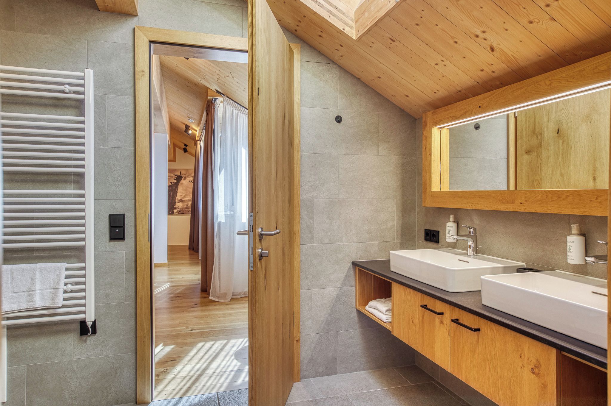 A modern bathroom with a wooden ceiling, two sinks, and a large mirror.