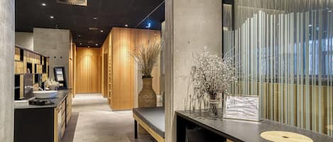 En modern hotellobby med en receptionsdisk, en sittgrupp och en väggpanel i trä med en dekorativ vas.