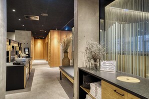 A modern hotel lobby with a reception desk, a seating area, and a wooden wall with a decorative vase. - All-Suite Resort Fieberbrunn (Fieberbrunn)